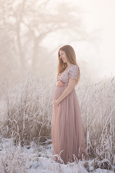 Mama in einem rosa-altrosa Tüllkleid mit Glitzer-Paillettenoberteil steht im Schnee und Nebel – Wintershooting Stuttgart.