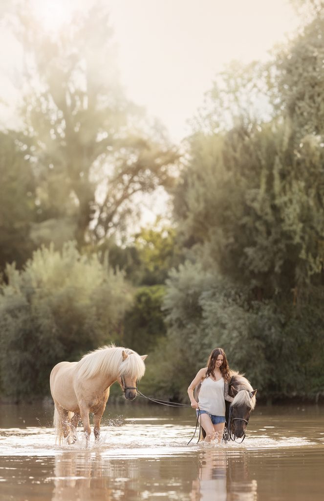 Frau mit ihren zwei Island Pony im Fluss, ein Pferd ist Isabel farben das andere ist ein Falbe. Die bilder sin im Sonmmer bei einem Pferde-Foto-Shooting mit Sonja Auer entstanden