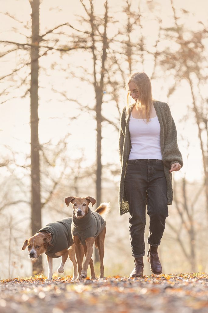 Frau und Hund laufen gemeinsam durch die Natur, ein natürlicher Alltagsmoment voller Leichtigkeit und Bewegung.